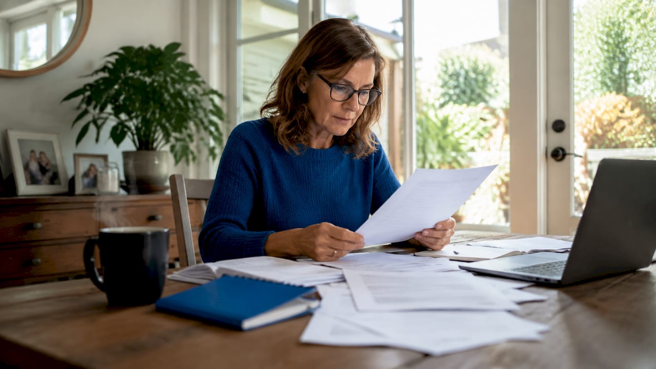 1782549205271_Homeowner-reviewing-bridge-loan-papers-at-kitchen-table Homeowner reviewing bridge loan papers at kitchen table